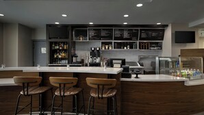 A modern bar area with a counter, stools, and a menu board. - Courtyard by Marriott Kokomo (Kokomo)