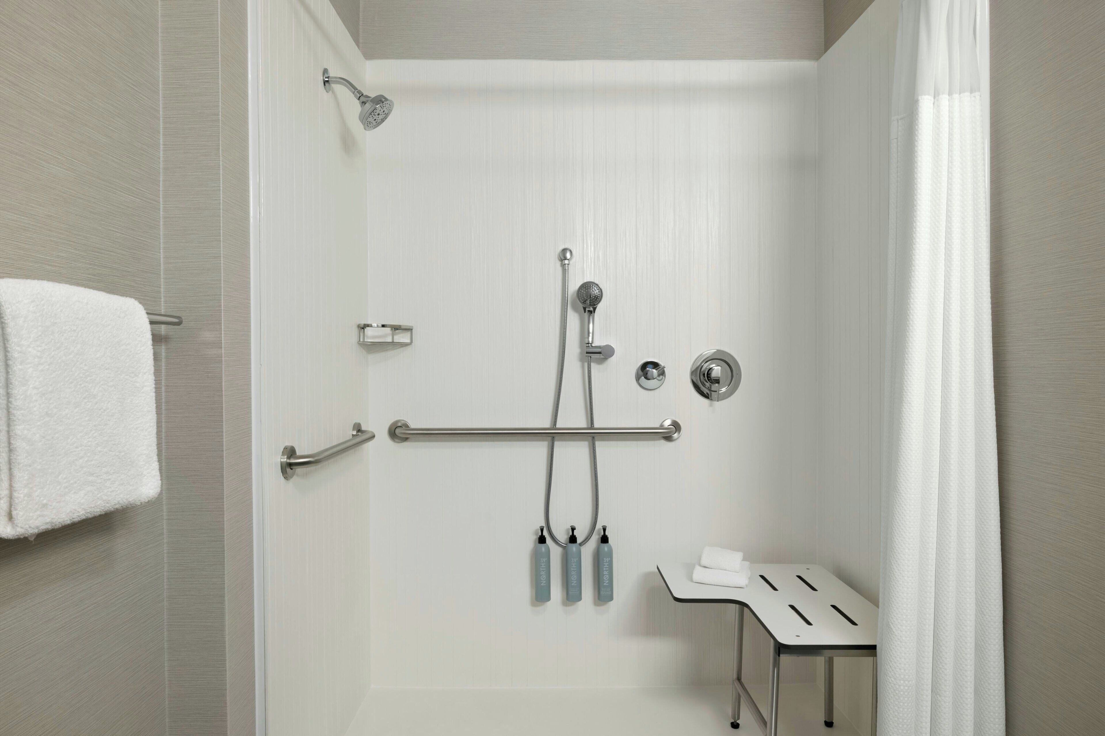 A modern shower with a handheld showerhead, a handheld showerhead, and a handheld showerhead.
