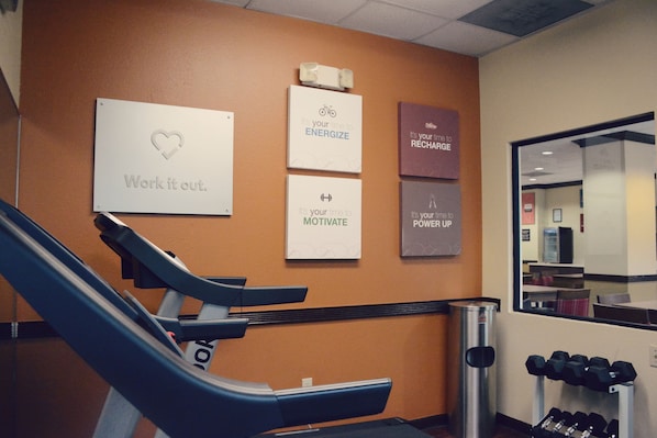 A gym with exercise equipment, motivational posters, and a mirror reflecting the room. - Blue Hotel IAH (Houston)