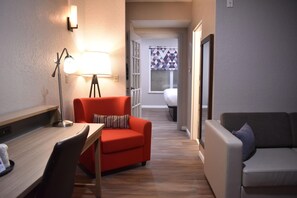 A compact living space with a red sofa, a grey sofa, a wooden table, and a floor lamp. - Blue Hotel IAH (Houston)