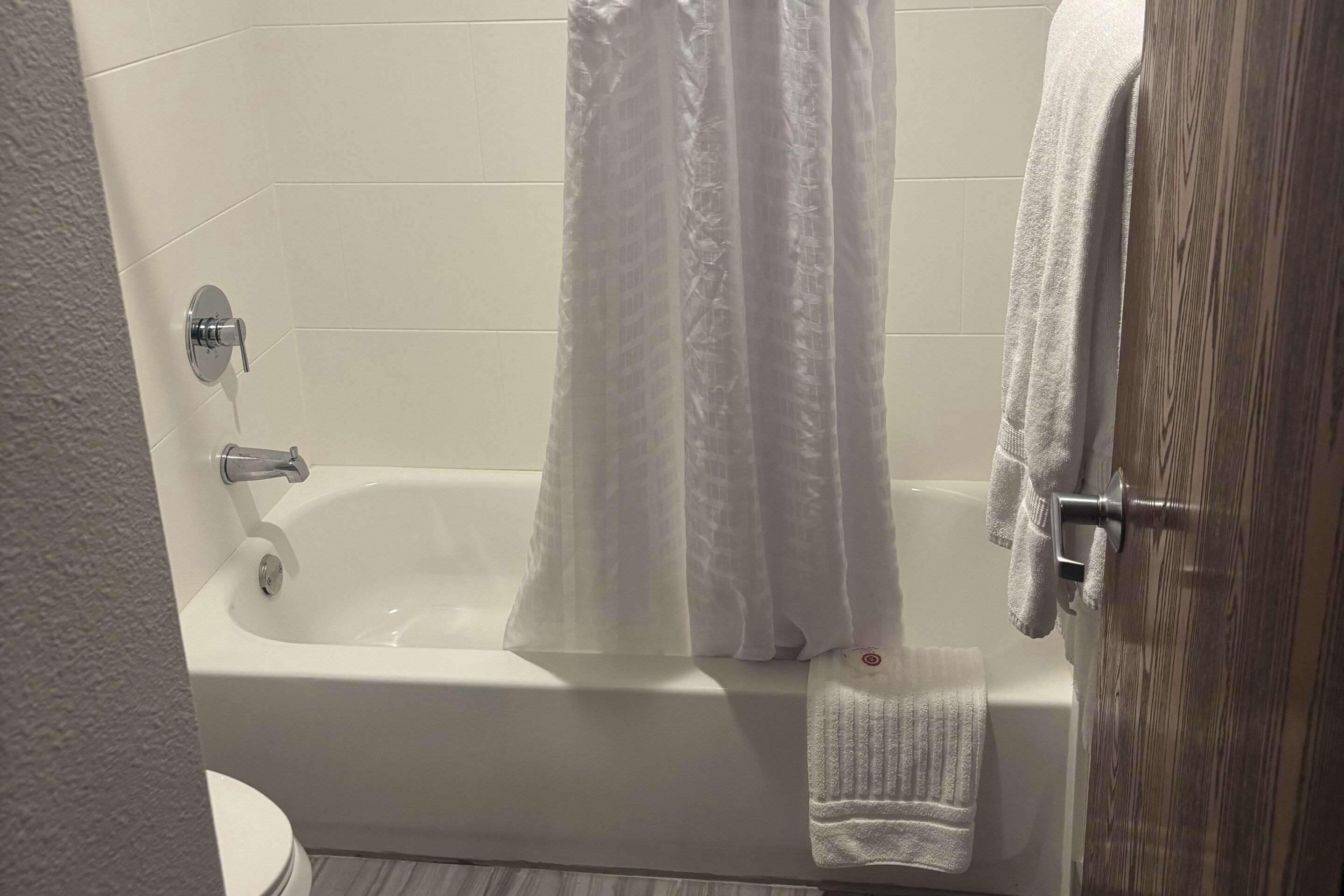 A bathroom with a bathtub, a shower curtain, and a towel rack.