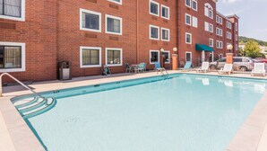 A swimming pool with a brick building in the background, lounge chairs, and a covered area. - Comfort Inn & Suites Brentwood - Nashville (Brentwood)
