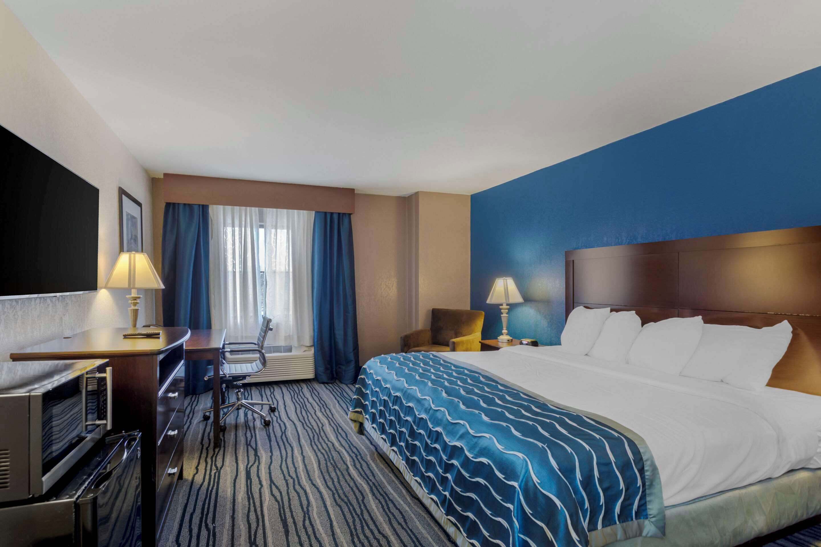 Una habitación de hotel con cama, escritorio, silla y televisor.