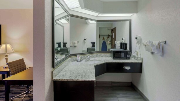 A hotel bathroom with a large mirror, a sink, a microwave, and a towel dispenser. - Comfort Inn & Suites Brentwood - Nashville (Brentwood)