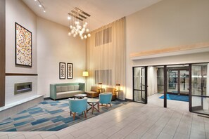 A modern hotel lobby with a fireplace, seating area, and a glass door entrance. - Holiday Inn Express Heber City by IHG (Heber City)
