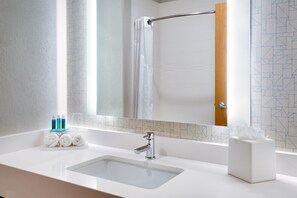 A bathroom with a white sink, a mirror, a shower curtain, and toiletries on the counter. - Holiday Inn Express Heber City by IHG (Heber City)