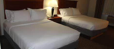 A hotel room with two beds, a nightstand with a lamp, and a clock.