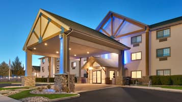 A hotel entrance with a covered walkway, stone pillars, and a well-maintained lawn.