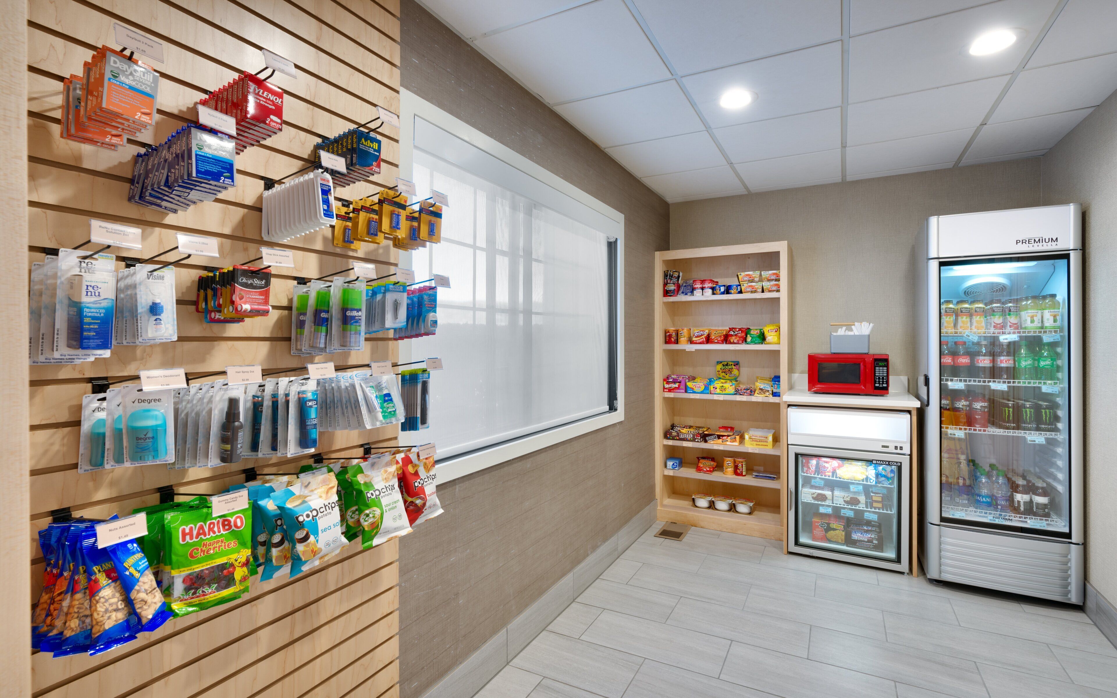 Una tienda con estantes llenos de diversos productos, un refrigerador y un microondas.