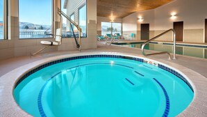 Une piscine intérieure à l’eau d’un bleu limpide, avec des bords carrelés et un plafond en bois.