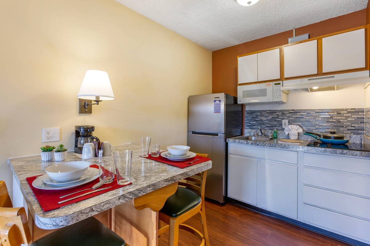 A modern kitchen with a marble countertop, white cabinets, and a built-in microwave.