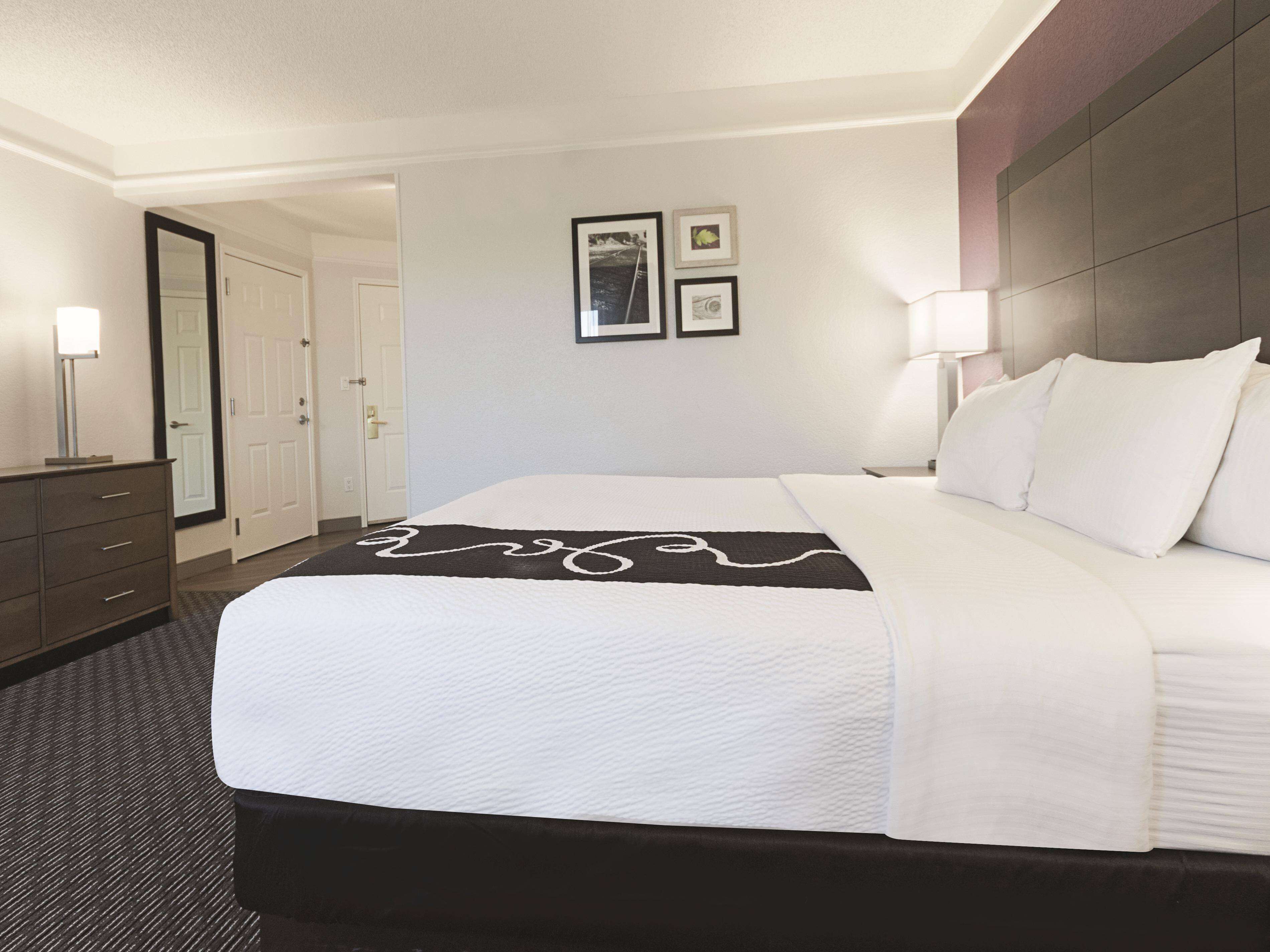 Una habitación de hotel con una cama grande, un aparador, un espejo y cuadros en la pared.