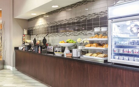A breakfast bar with a variety of food items, including fruits, pastries, and dairy products.