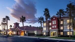 A multi-story hotel with a red and beige facade, palm trees, and a parking lot. - Residence Inn By Marriott Las Vegas/Green Valley (Henderson)