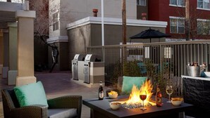 An outdoor patio with a grill, seating, a fire feature, and a table set for dining. - Residence Inn By Marriott Las Vegas/Green Valley (Henderson)
