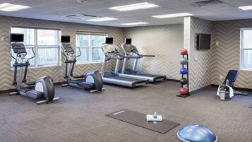 A gym with treadmills, elliptical machines, a rowing machine, and a blue balance ball.