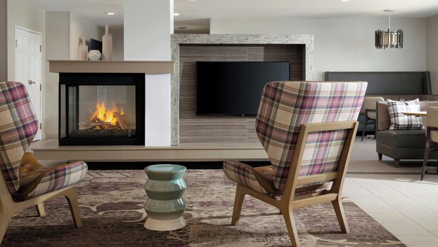 A modern living room with a fireplace, two plaid armchairs, a coffee table, and a flat-screen TV mounted above the fireplace. - Residence Inn By Marriott Las Vegas/Green Valley (Henderson)