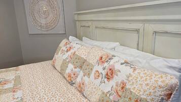A neatly made bed with floral bedding, a headboard, and a decorative wall piece.