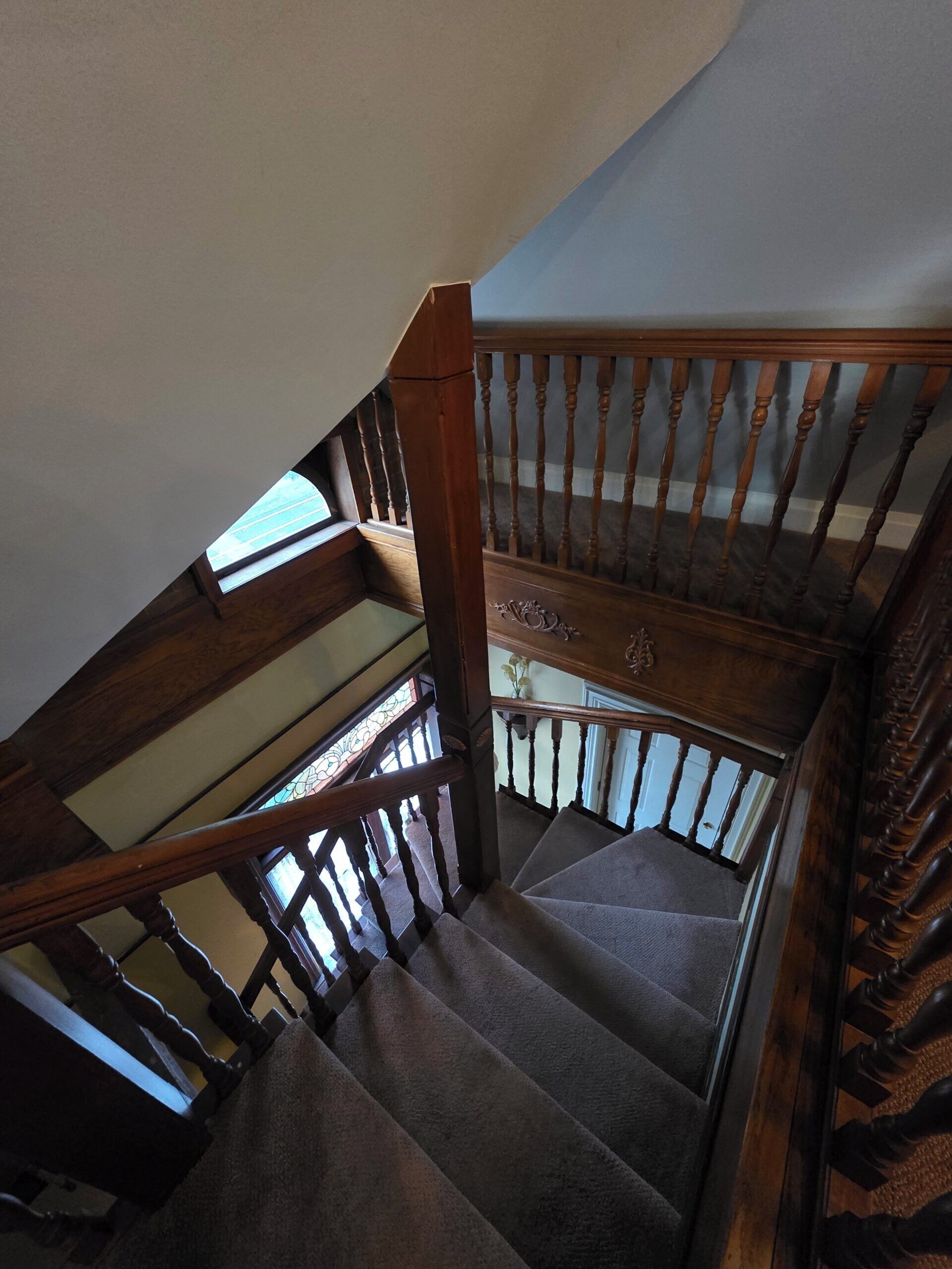 A wooden staircase with a handrail and carpeted steps.