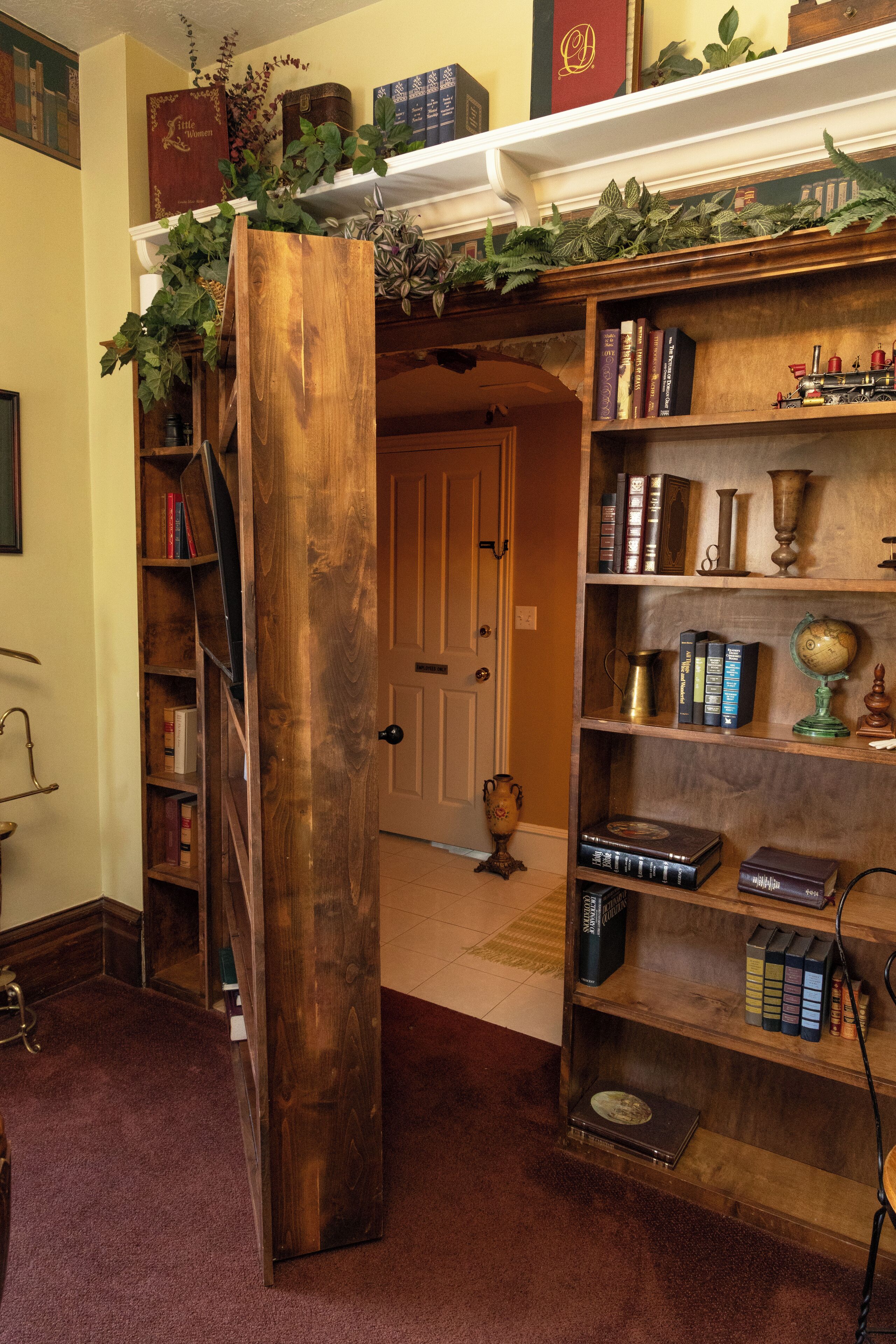 A room with a wooden bookshelf, a door, and a carpeted floor.