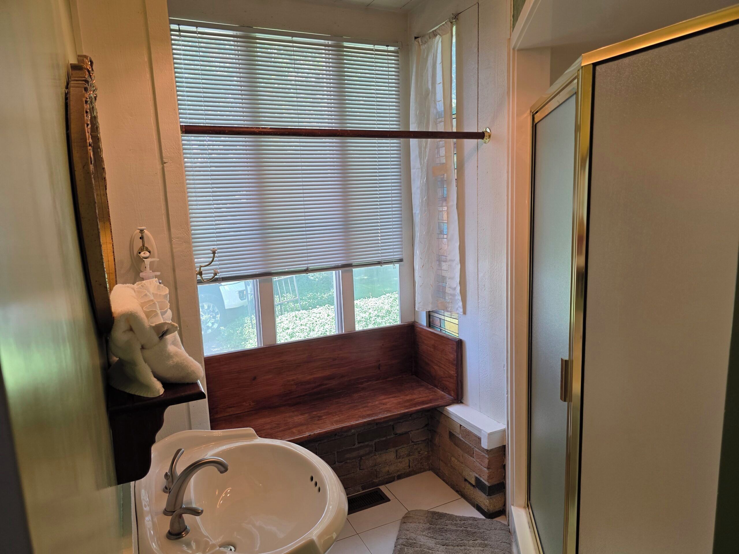 Un baño con bañera, lavamanos y ventana con persianas.