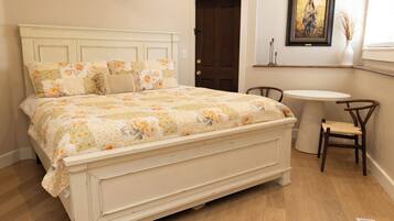 Un dormitorio con una cama grande, una mesita redonda y una silla.