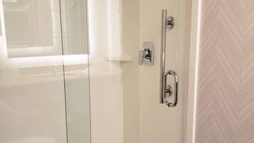 A modern bathroom with a glass-enclosed shower, a handheld showerhead, and a wall-mounted faucet.