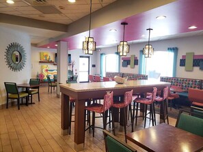 A restaurant with a central island, booths, and a colorful wall mural.