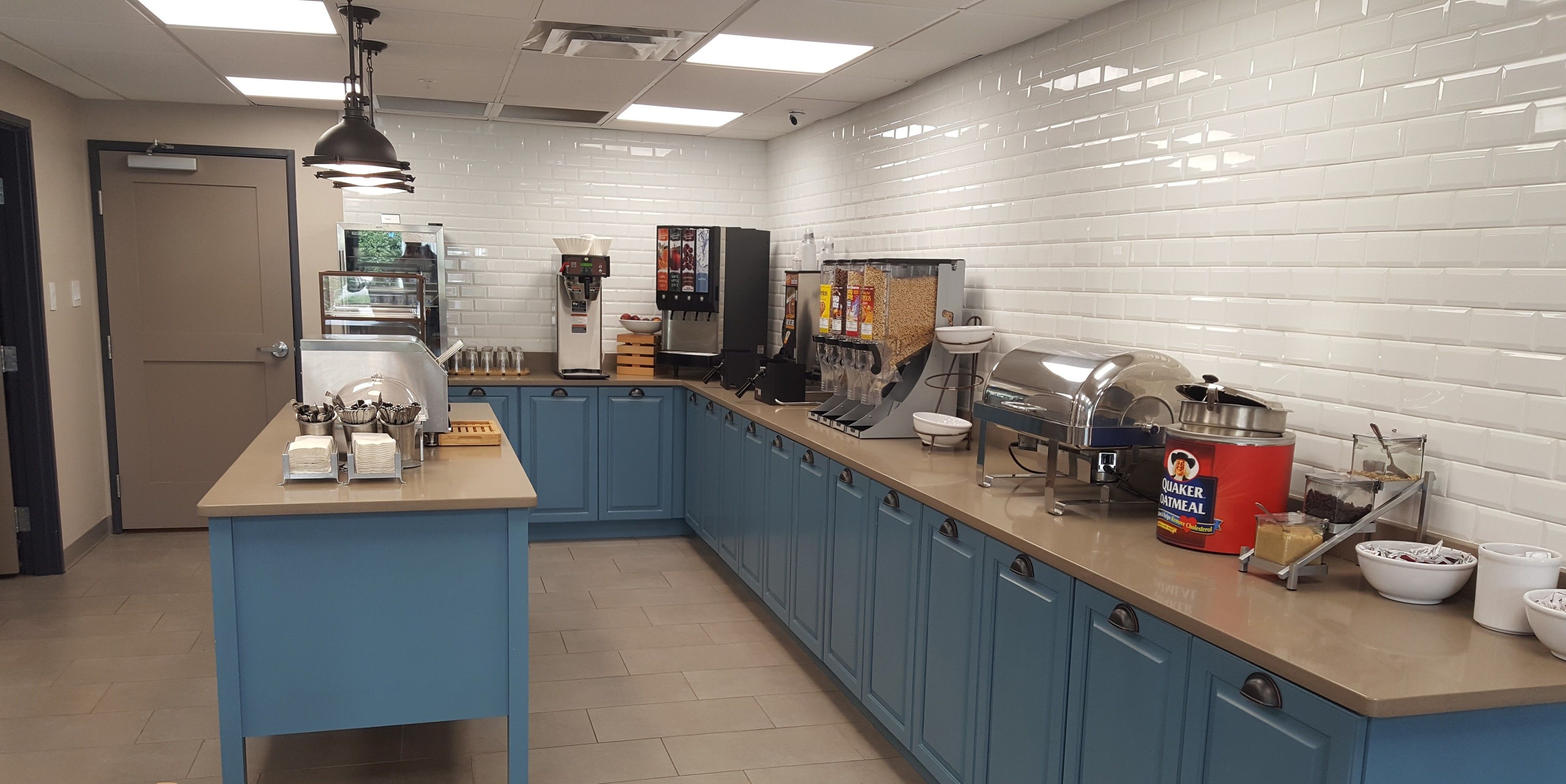 A kitchen area with blue cabinets, a coffee machine, a food warmer, and a kettle.