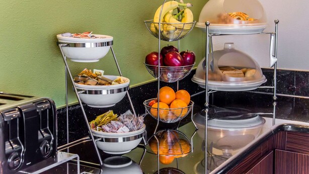 A buffet setup with multiple bowls containing fruits, vegetables, and bread. - Sleep Inn Matthews - Charlotte (Matthews)