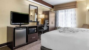 A hotel room with a bed, a desk with a television, a chair, a desk lamp, and a window with curtains. - Sleep Inn Matthews - Charlotte (Matthews)