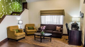 A living room with a sofa, two armchairs, a coffee table, a desk with a computer, and a staircase. - Sleep Inn Matthews - Charlotte (Matthews)