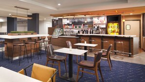 A modern bar area with a counter, stools, and tables. - Courtyard by Marriott Florence (Florence)