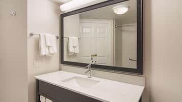 A bathroom with a white sink, a mirror, and a towel rack.