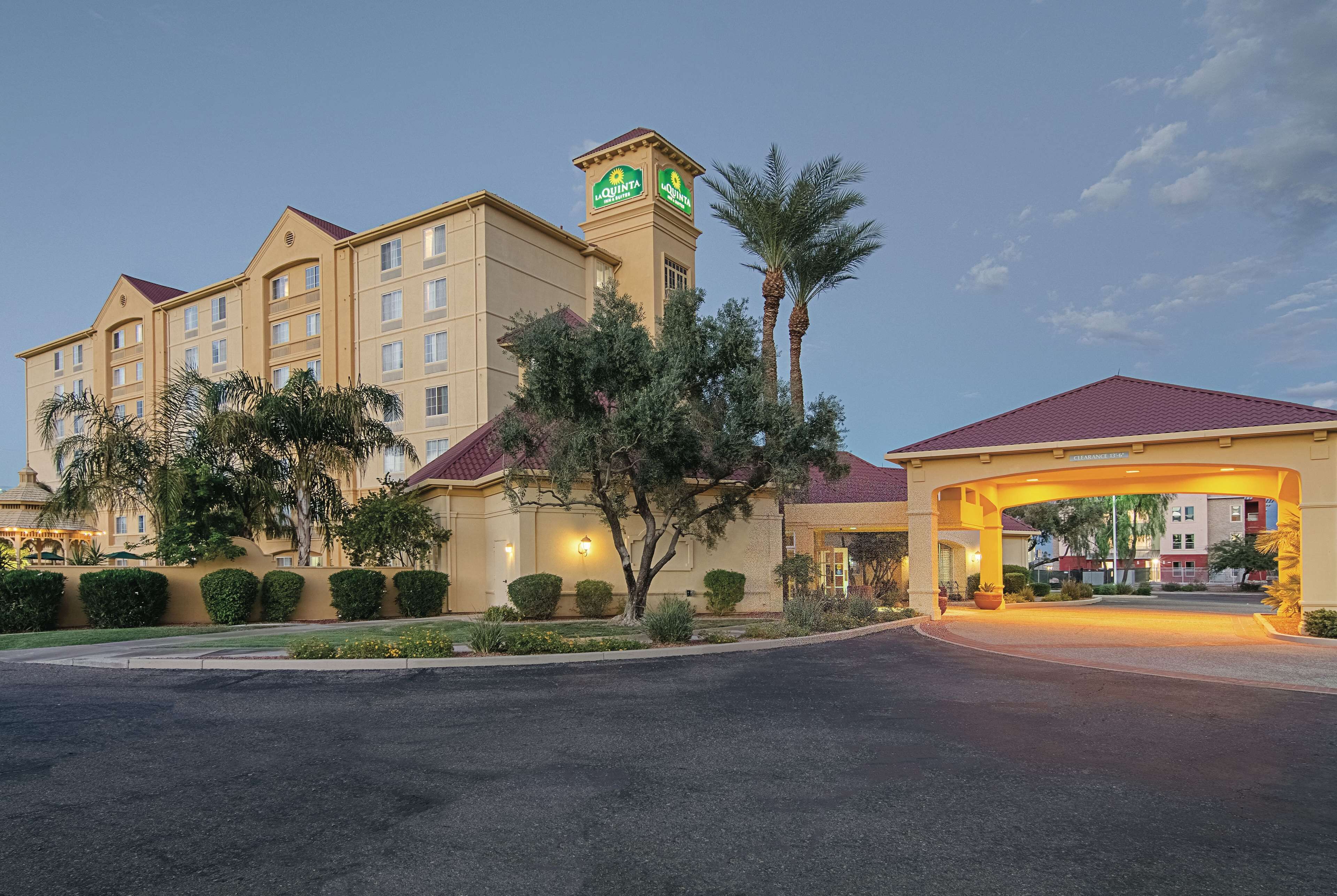 A hotel with a prominent tower, a well-lit entrance, and a landscaped driveway.