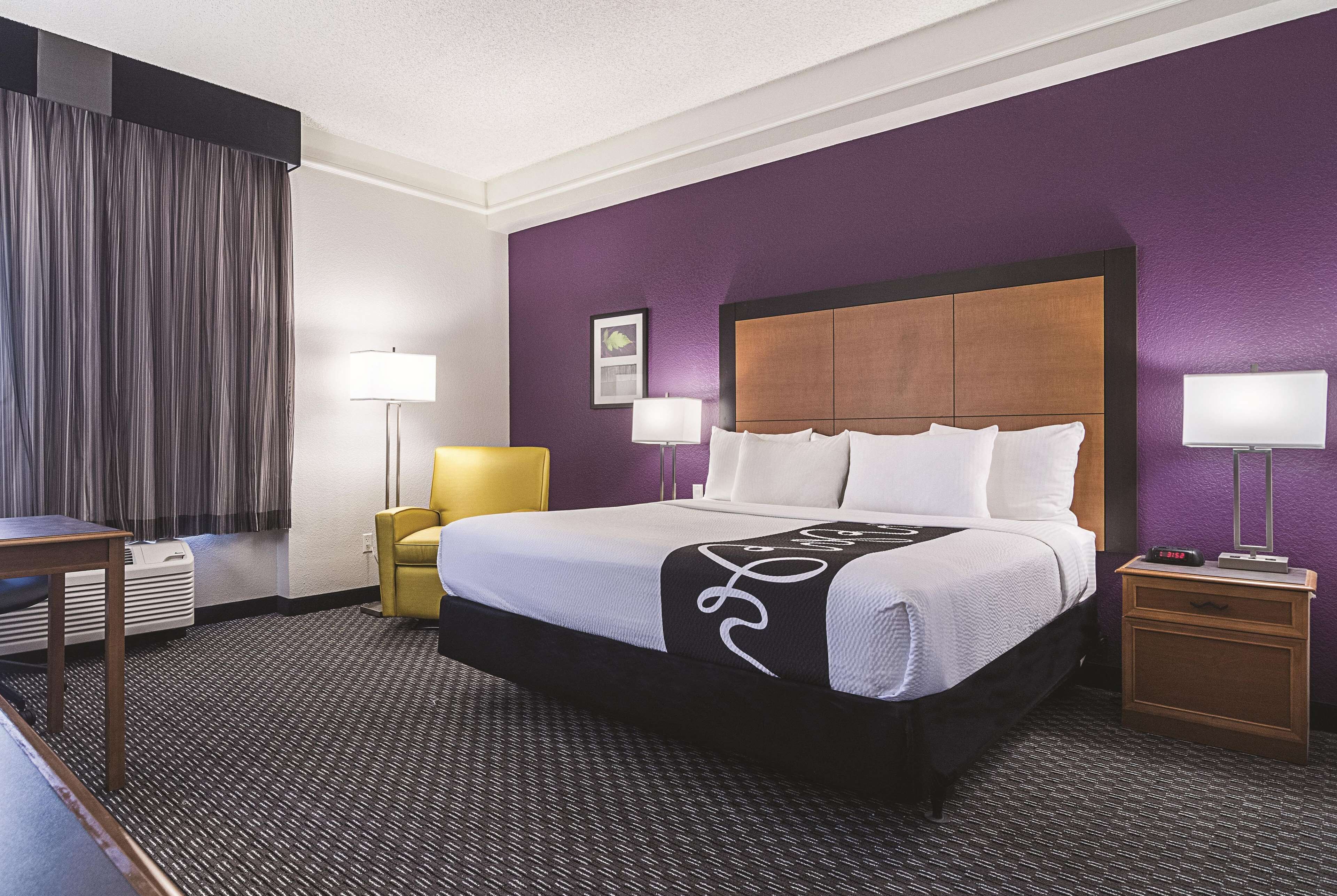 A hotel room with a large bed, two bedside tables, a chair, and a desk.