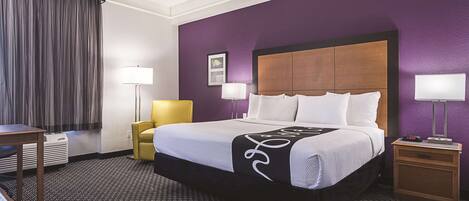 A hotel room with a large bed, two bedside tables, a chair, and a desk.