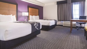 Une chambre d’hôtel avec deux lits, un bureau et une fenêtre avec des rideaux.