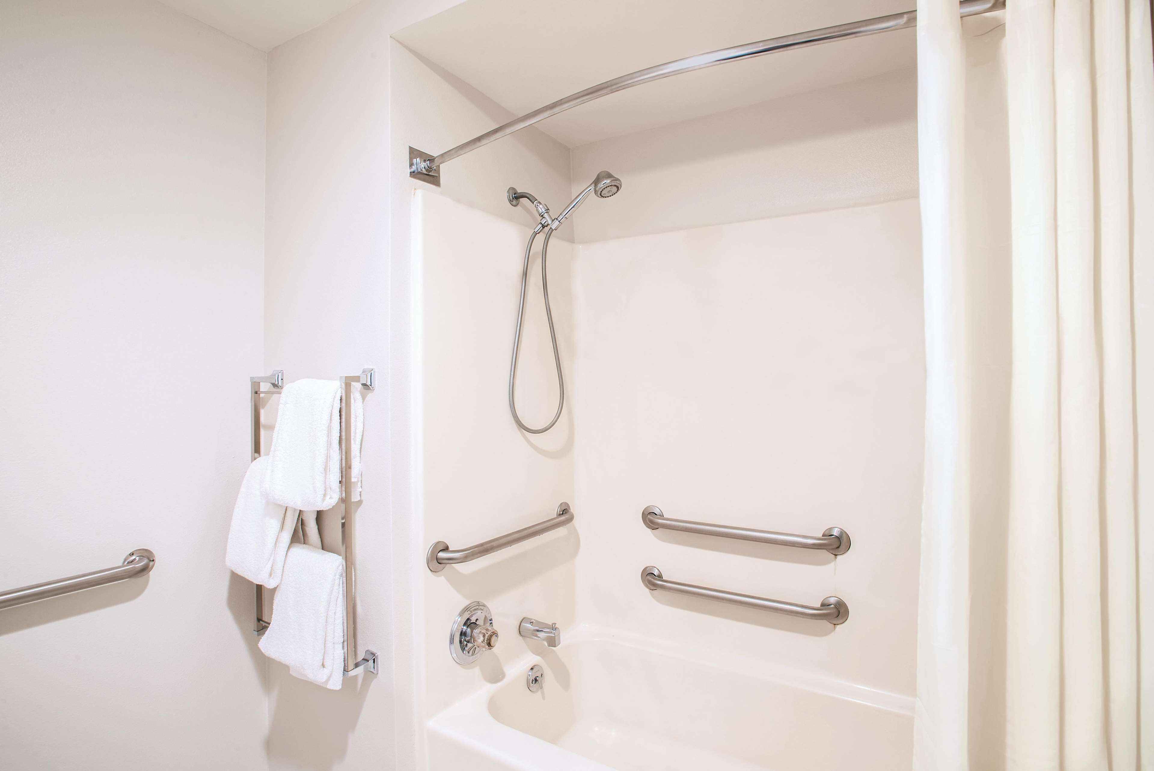 A bathroom with a bathtub, grab bars, and a towel rack.