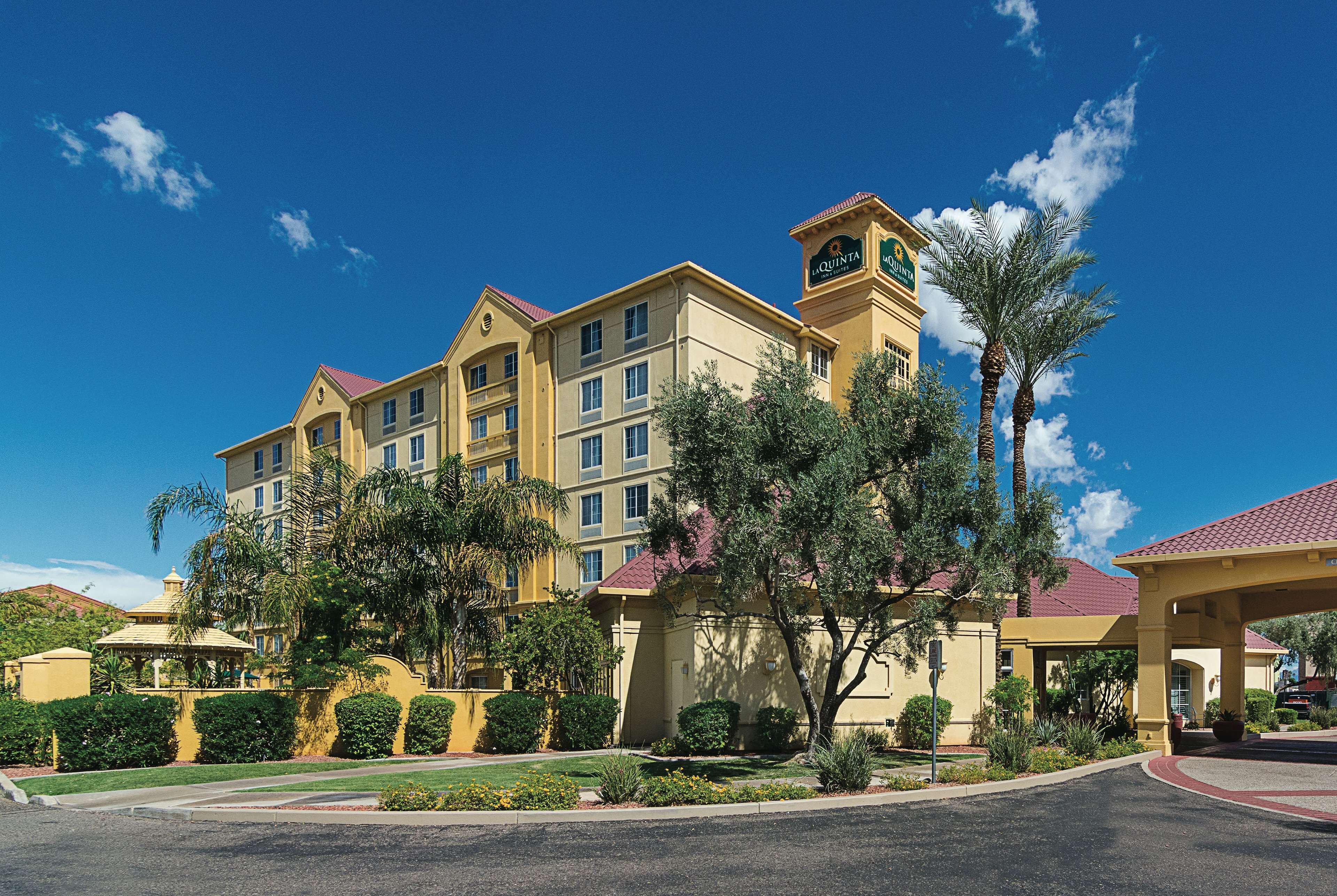 A multi-story hotel with a central clock tower, surrounded by landscaped gardens and palm trees.