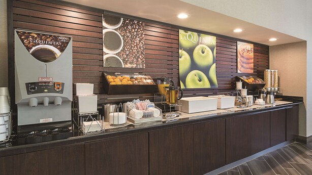 Un bar à petit-déjeuner équipé de machines à café, d’un présentoir de fruits et d’un distributeur de boissons.