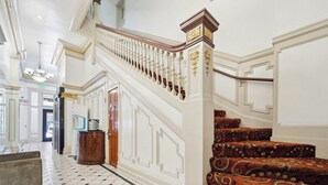 A grand staircase with ornate balustrades and a patterned carpet, leading to an upper floor. - Union Square Plaza Hotel (San Francisco)