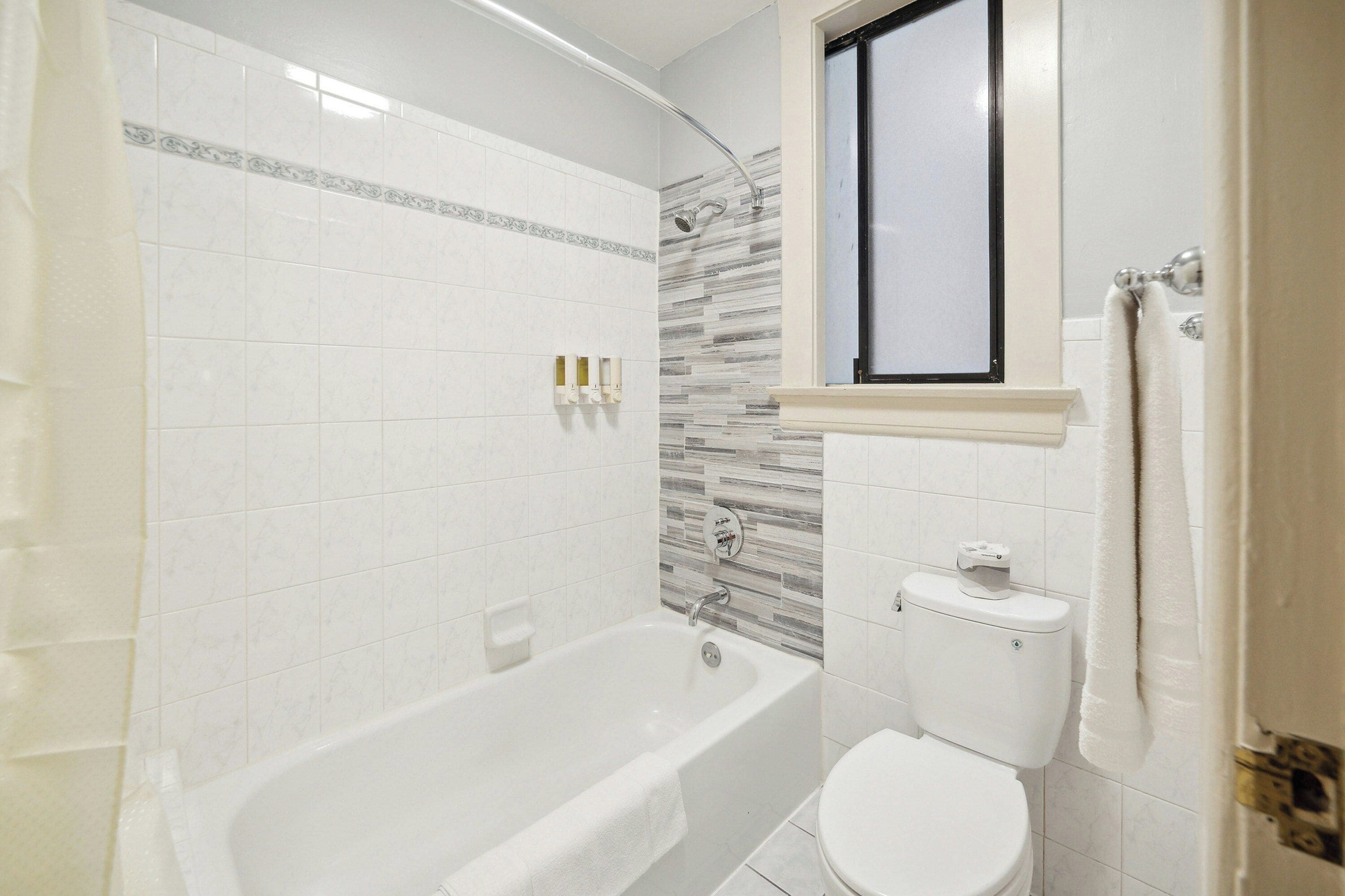 Ein Badezimmer mit Badewanne, Toilette und Duschbereich.