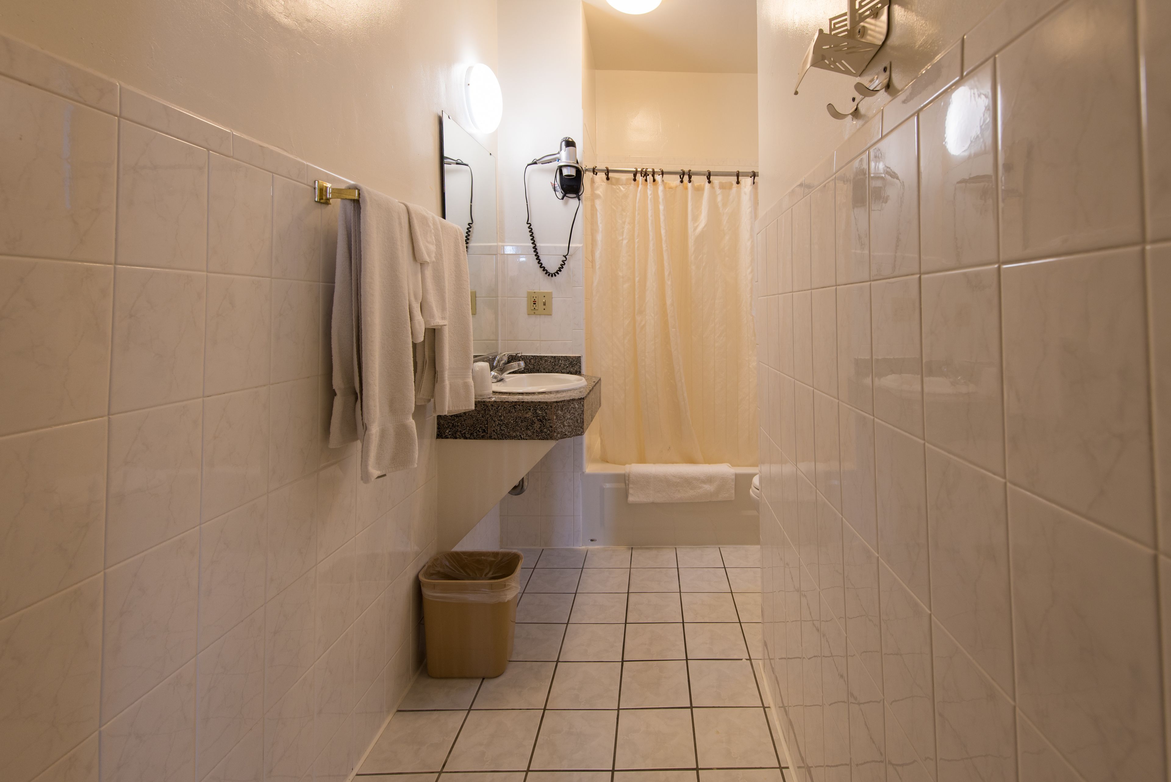 A narrow bathroom with a sink, mirror, and towel rack.