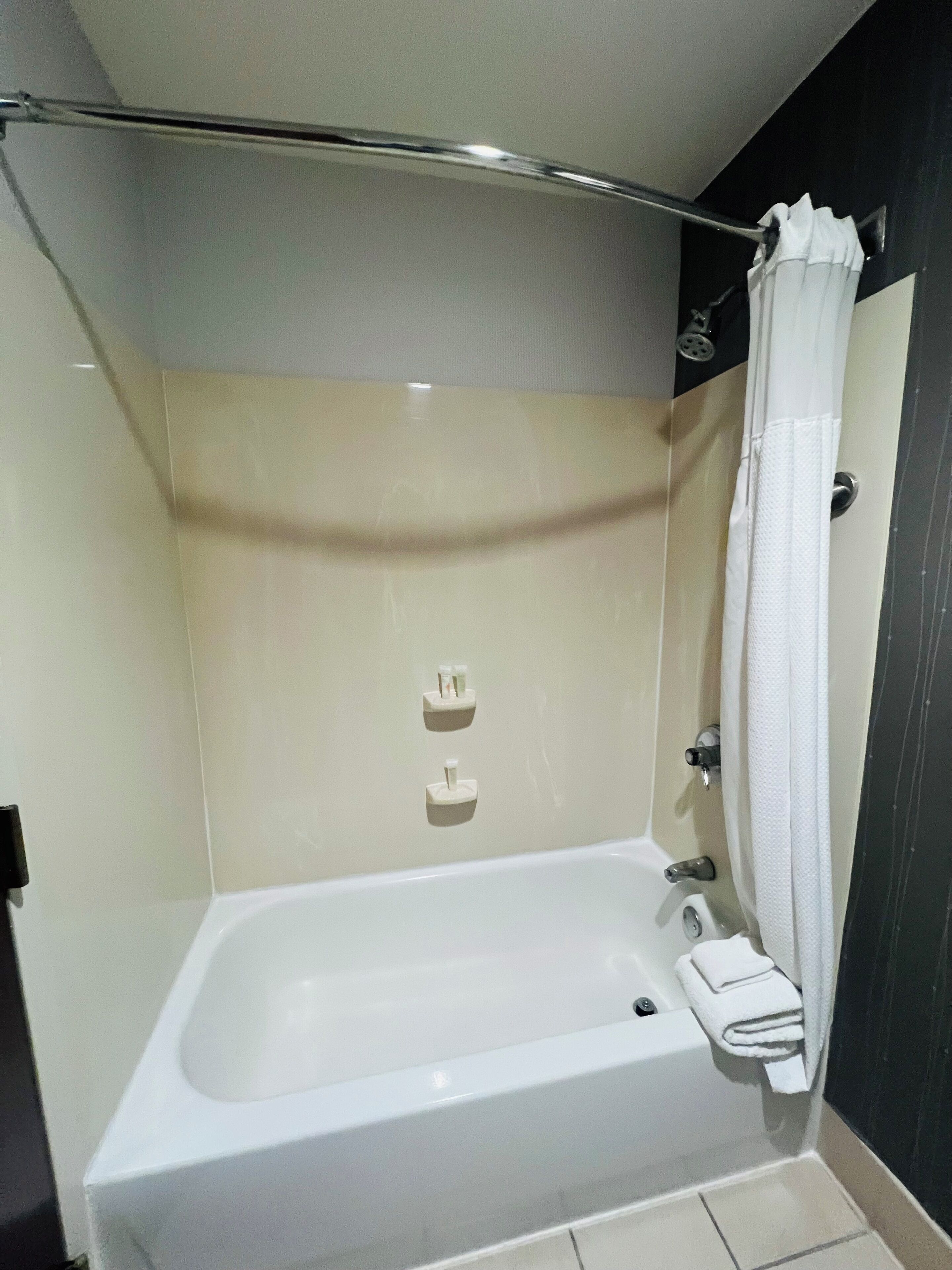 Ein modernes Badezimmer mit einer Badewanne, einer Duschvorhang und zwei Handtuchhaltern.