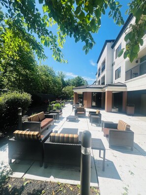 Un espace extérieur aménagé avec des meubles en osier et une terrasse couverte.