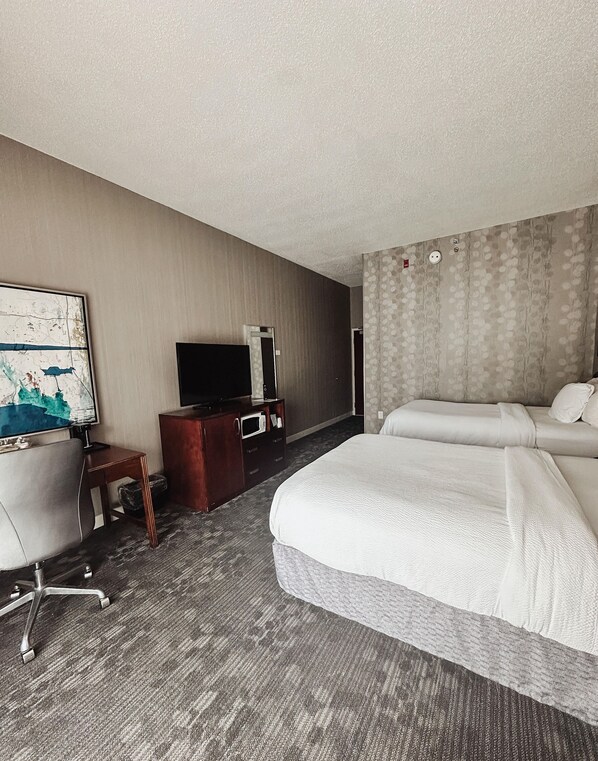 Habitación de hotel con una cama grande, un escritorio con televisor de pantalla plana, una mesita y una silla.