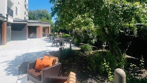 A courtyard with outdoor seating, a covered area, and lush greenery.