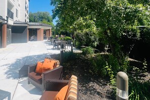 A courtyard with outdoor seating, a covered area, and lush greenery.