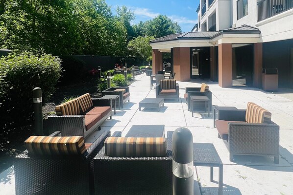 Un espace extérieur aménagé avec des meubles en osier et une partie abritée.